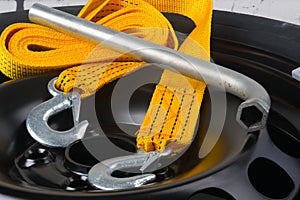 Close-up of the tow rope and key for removing the wheel, against the background of the metal black disc of the car