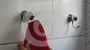 Close-up of a towel rack in the bathroom. man hangs a red towel on the hook of the hanger