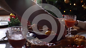 Close-up tracking shot of young man putting dish with baked hot turkey on dinner table served for Christmas family party