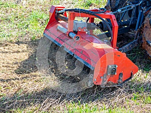 Close-up of a tractor with a chain mower chopping dry grass. Maintenance of the territory, mulching of grass, agricultural
