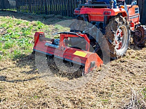 Close-up of a tractor with a chain mower chopping dry grass. Maintenance of the territory, mulching of grass, agricultural