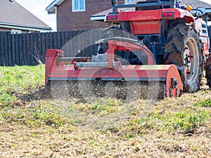 Close-up of a tractor with a chain mower chopping dry grass. Maintenance of the territory, mulching of grass, agricultural