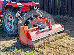 Close-up of a tractor with a chain mower chopping dry grass. Maintenance of the territory, mulching of grass, agricultural