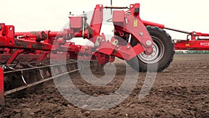 Close-up, tractor cultivator cultivates, digs the soil. tractor plows the field. automated tiller for digging soil in