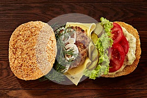 Close-up of traditional american burger with lettuce, cheese, onion and tomato on wooden background