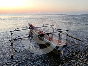 A close up of traditional fishing boat mooring on calm beach on sunset