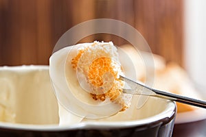 Close up. Traditional french cheese fondue. Crouton dipped into hot cheese fondue on a long-stemmed fork. Winter seasonal meal.