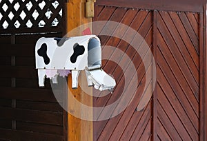 Close-up of traditional mailbox, metal box in the form of a cow with a red lever for the postman on a wooden fence, communication