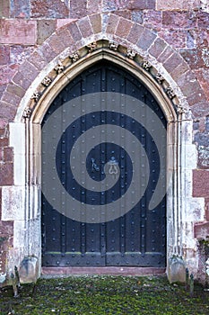 Close-up of traditional medieval wood entrance doorway with ancient brick arc in Crediton Parish Church of the Holy Cross and the