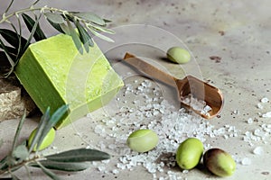 Close up of traditional natural organic olive soap. Handmade soap bar, green olives and leaves and wooden spoon of sea solt on