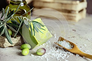 Close up of traditional natural organic olive soap. Handmade soap bar, green olives, olive branch and wooden spoon of sea solt on