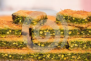 Close up of traditional oriental sweet pastry cookies known as kanafeh, Turkish desert with sugar, honey and pistachio,  in displa