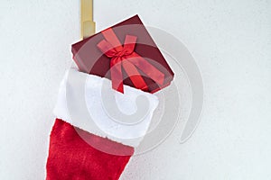 Close up of traditional red and white plush Christmas stocking stuffed with red wrapped present