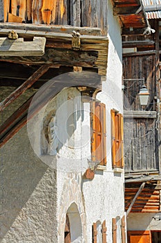 Close-up on traditional wooden houses in Saint Veran village with a white statue of virgin Mary in the foreground