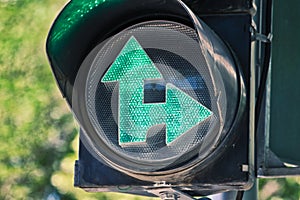 Close-up traffic light photo with luminous green arrows on blurred green background