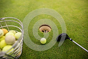 Close up of training golf balls and club on the playground close to the hole, sport concept