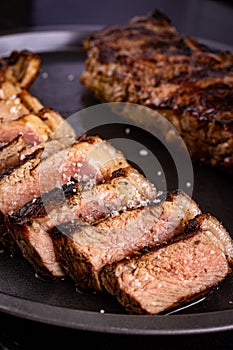 Close-up of a tray containing grilled meat, drizzled with a savory sauce