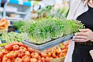 Close-up of trays with various microgreens in hands of woman at farmer's market