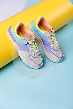 Close up of trendy colored sneakers for teenage girls on colorful yellow-blue background.