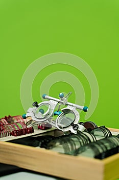 Close-up trial frame glasses and set of lenses on green background. Ophthalmology equipment to examine eye visual system