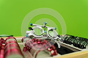 Close-up trial frame glasses and set of lenses on green background. Ophthalmology equipment to examine eye visual system