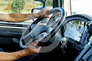 Close up of truck driver behind the steering wheel in a cabin