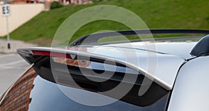 Close-up on the trunk lid of a gray car with a plastic spoiler over the rear window to improve the aerodynamics of the car body