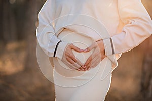 Close up tummy of pregnant woman making heart shape with hands