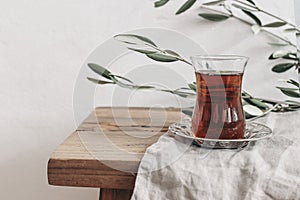 Close-up of Turkish black tea in glass on silver saucer. Ramadan Kareem greeting card, invitation. Green olive tree