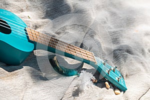 Close up turquoise color ukulele guitar neck on linen cloth background on sunny weather