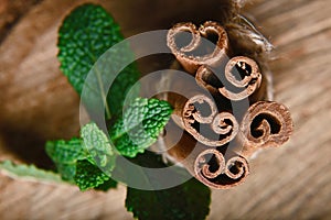 Close-up twisted sticks of cinnamon bundle, green leaves of fresh mint, selective focus, marco, set