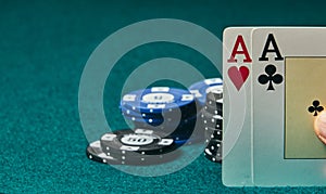 close-up of two aces held in one hand on the green game mat on the right side of the image to leave place for editing, poker chips