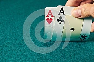 close-up of two aces held in one hand on the green game mat on the right side of the image to leave room for editing