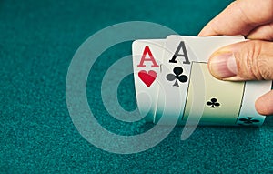 close-up of two aces held in one hand on the green game mat on the right side of the image to leave room for editing