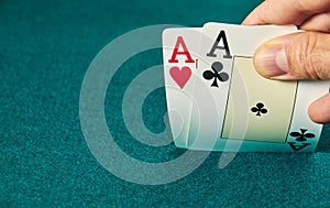 close-up of two aces held in one hand on the green game mat on the right side of the image to leave room for editing