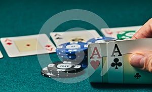 close-up of two aces held in one hand on the green game mat on the right side of the image to leave room for editing, other cards