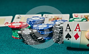 close-up of two aces held in one hand on the green game mat on the right side of the image to leave room for editing, other cards