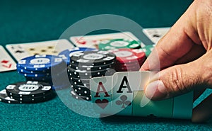 close-up of two aces held in one hand on the green game mat on the right side of the image to leave room for editing, other cards