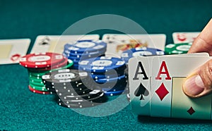 close-up of two aces held in one hand on the green game mat on the right side of the image to leave room for editing, other cards