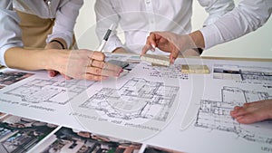 Close Up Of two Architects Discussing Plan Together At Desk With Blueprints