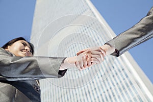 Close up of two business people shaking hands by the china world trade center in Beijing