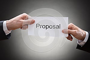 Close-up of two businessman's hand holding proposal paper