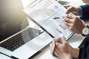 Close-up Of Two Businesspeople Discussing Graph In Office