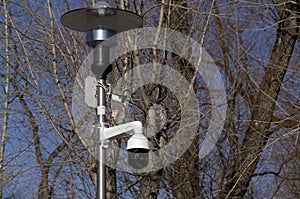 Close up two CCTV cameras are installed on lamp post  in the green park public