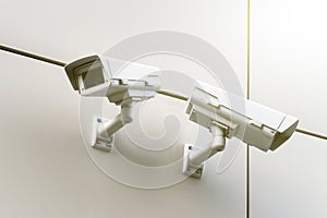 close-up of two CCTV cameras on a white wall on the street