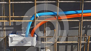 CLOSE UP: Two colorful corrugated conduits run out of a socket set on outer wall