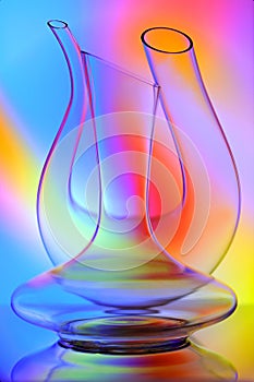 Close up of two elegant curved crystal wine decanters on colorful background photo