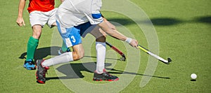 Close up of two field hockey players, challenging eachother for the control and posession of the ball during an intense, competiti