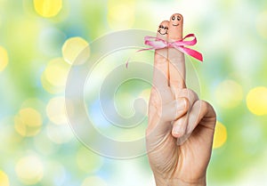 Close up of two fingers tied by pink bow knot