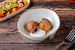 Close-up of two fried croquettes served with creamy dip